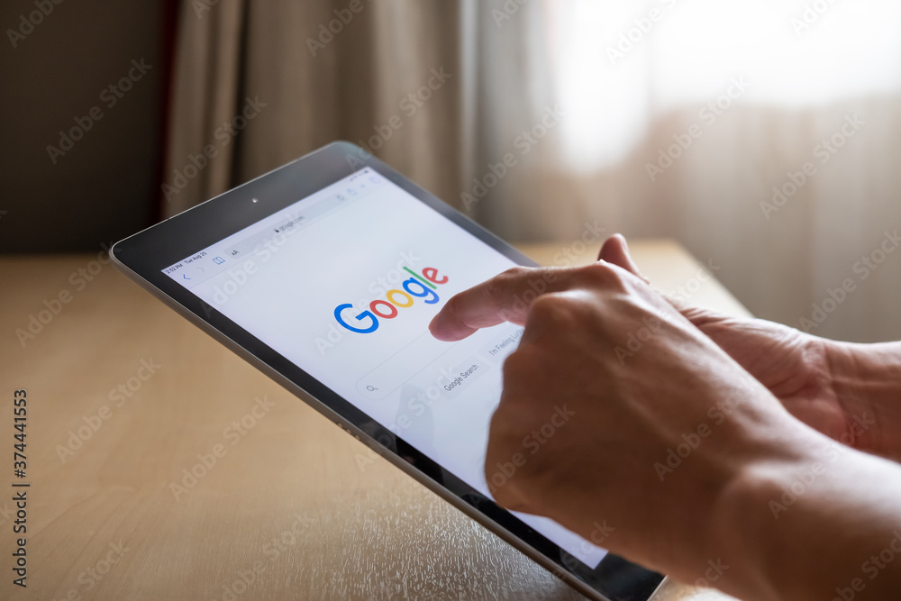 Bangkok, Thailand 25 AUG 2020. Men hand using digital tablet for search information on Google.  Wireless Smartphone technology with intelligence search engine.
